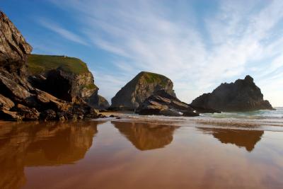 Reflections of rock formations in the wet sand at Bedruthan Step