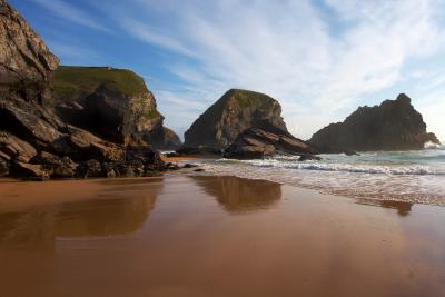 Reflections of rock formations in the wet sand at Bedruthan Step